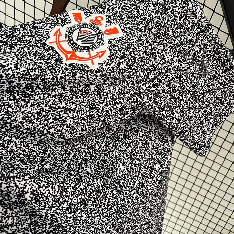 Camisa Corinthians 2023/24 Edição Especial Nike Torcedor Masculina com estampa preta e branca estilo caderno universitário, escudo bordado e logo Nike vermelho, pendurada em cabide contra uma grade metálica.
