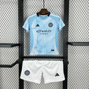 Kit Infantil New York City Home 2025/26 Adidas – Camisa azul clara com detalhes geométricos inspirados nos prédios de Nova York, calção azul marinho e meias combinando, modelo infantil