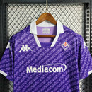 Camisa Fiorentina Home I 2023/24 Kappa Torcedor Masculina roxa com escudo bordado no peito, logo Kappa em destaque nos ombros, gola redonda moderna e tecido leve e respirável, perfeita para torcedores que valorizam estilo, conforto e tradição do clube italiano.