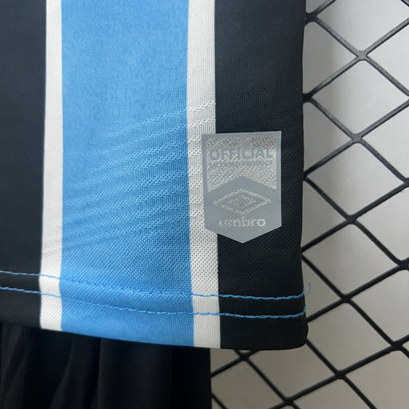 "Kit Infantil Grêmio Home 2024/25 Umbro, camisa azul, preta e branca listrada com shorts e meias combinando, uniforme oficial para crianças de 3 a 13 anos torcedoras do Grêmio."