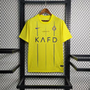 Camisa Al-Nassr Home (1) 2023/24 Nike Torcedor Masculina amarela com detalhes azuis, escudo do Al-Nassr e logo Nike bordados, modelo oficial usado por Cristiano Ronaldo."

