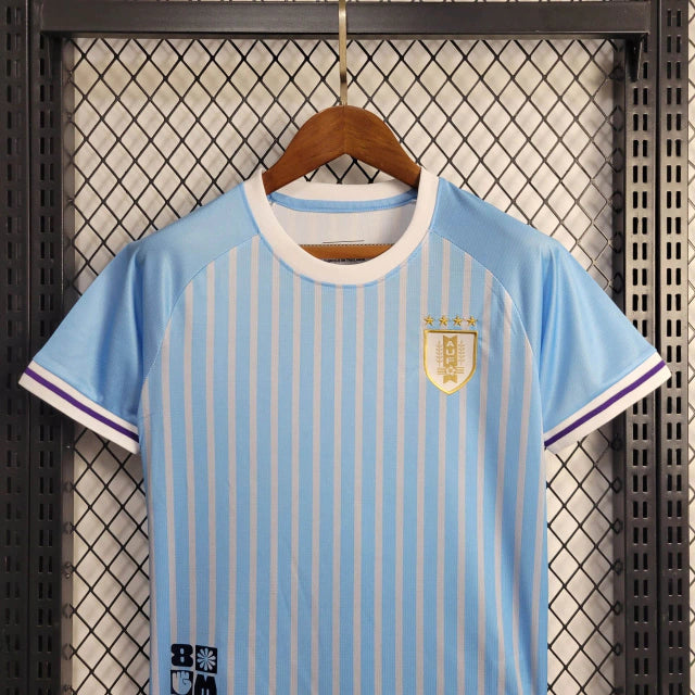 "Kit Infantil Uruguai Home (1) 2024/25 oficial, camisa celeste com escudo da AUF em destaque, shorts combinando, uniforme completo para crianças de 3 a 13 anos"
