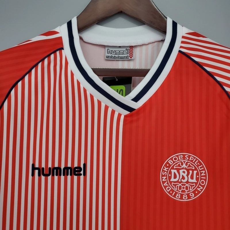 Camisa Dinamarca Home I 1986/87 Hummel Retrô Masculina, vermelha, com escudo da seleção dinamarquesa e logo Hummel bordados, feita em tecido leve e confortável, modelo retrô masculino com caimento tradicional, ideal para colecionadores e uso casual.”