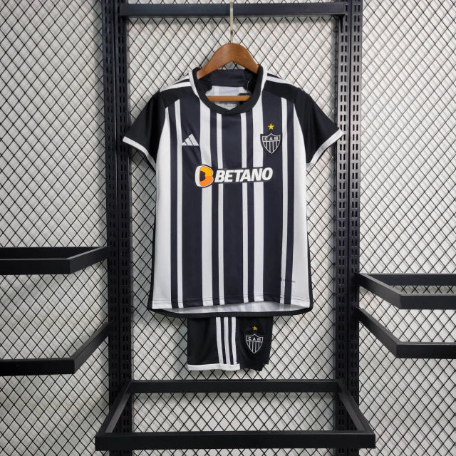 Kit Infantil Atlético Mineiro Home (1) 2023/24 Adidas – camisa listrada preta e branca com escudo bordado, shorts preto e meiões inclusos, uniforme oficial para pequenos torcedores do Galo."
