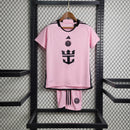 "Kit Infantil Inter Miami Home (1) 2024/25 Adidas oficial, camisa branca com detalhes em rosa e preto, escudo do Inter Miami CF em destaque, shorts e meias combinando, uniforme completo para crianças de 3 a 13 anos"