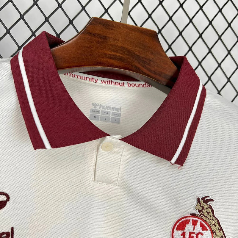 Camisa 1. FC Köln Retrô 2024/25 Hummel X WE:FC Torcedor Masculina branca com detalhes vermelhos e pretos, escudo retrô bordado do clube e logos Hummel e WE:FC, modelo oficial para torcedores do futebol alemão.