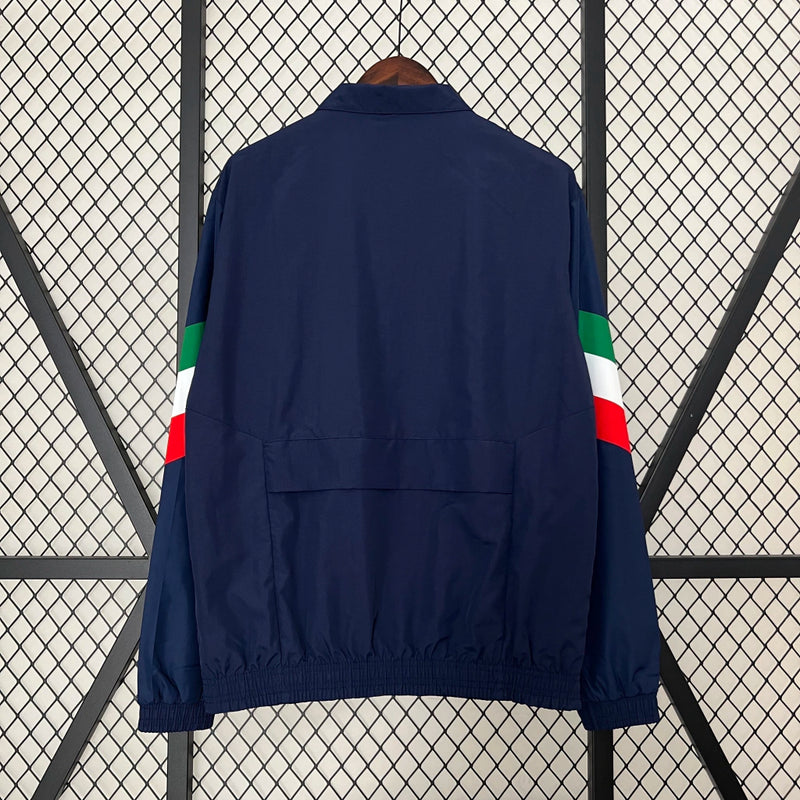 Corta-Vento Itália 2024/25 Adidas Masculino, azul, com escudo da seleção italiana e logo Adidas em destaque, tecido leve, respirável e resistente ao vento, com bolsos laterais e ajuste confortável, ideal para uso casual ou esportivo.”