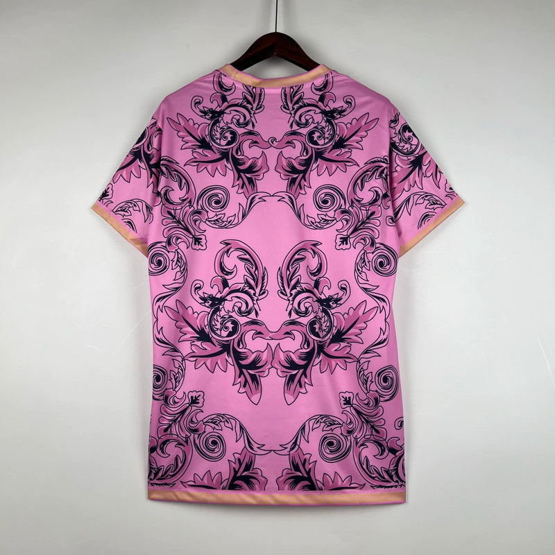 Camisa Concept Itália x Versace Puma Torcedor masculina, rosa, com escudo da seleção italiana no peito, detalhes exclusivos da Versace e três listras Puma nos ombros, feita em tecido leve e respirável, modelo com caimento confortável, ideal para torcer com estilo e exclusividade.