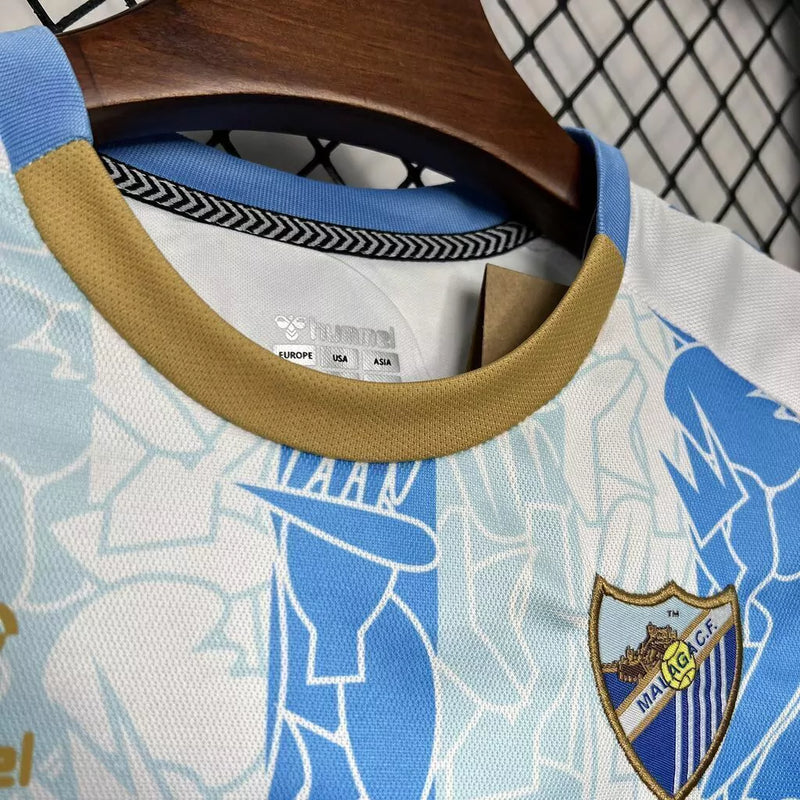 Kit Infantil Málaga CF Home I 2024/25 Hummel com camisa e short, uniforme infantil azul, tecido leve e respirável, ideal para jogos, treinos e jovens torcedores do Málaga CF."