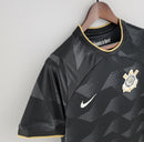 Camisa Corinthians Away II 2022/23 Nike Torcedor Masculina na cor preta com detalhes dourados, escudo bordado no peito esquerdo e logo Nike no lado direito, pendurada em cabide sobre fundo branco.