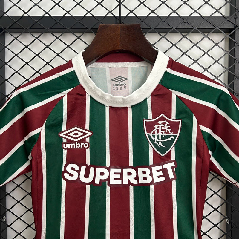 Kit Infantil Fluminense Home 2025/26 Umbro, camisa tricolor verde, grená e branca com shorts e meias combinando, uniforme oficial para crianças de 3 a 13 anos torcedoras do Fluminense."