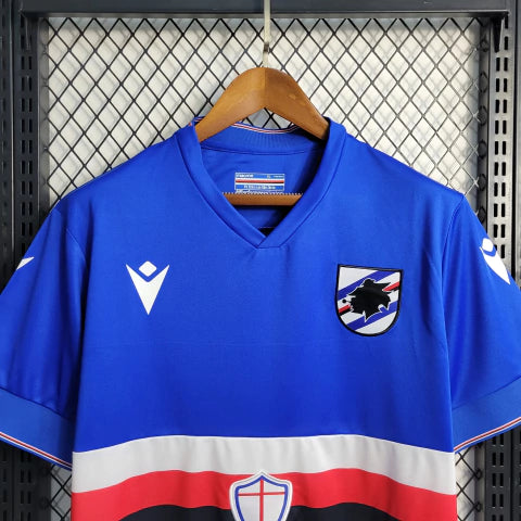 Camisa Sampdoria Home I 2022/23 Torcedor Masculina Azul com faixas branca, vermelha e preta no peito, escudo bordado e design clássico do clube italiano.”