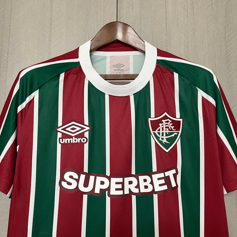 
Camisa Fluminense Home 2025/26 Umbro Torcedor Masculina tricolor com listras verticais em verde, grená e branco, escudo bordado no peito e design moderno da temporada 2025/26