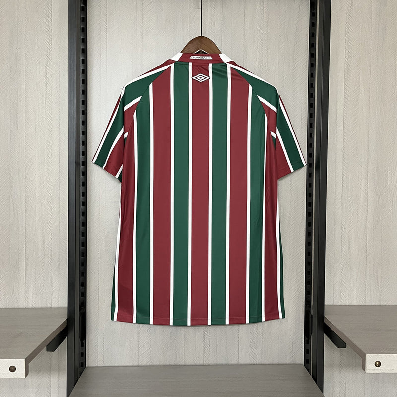 
Camisa Fluminense Home 2025/26 Umbro Torcedor Masculina tricolor com listras verticais em verde, grená e branco, escudo bordado no peito e design moderno da temporada 2025/26
