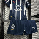 Kit Infantil Rayados de Monterrey 2024/25 Puma oficial, camisa listrada azul e branca com escudo do clube em destaque, shorts combinando, uniforme completo para crianças de 3 a 13 anos"