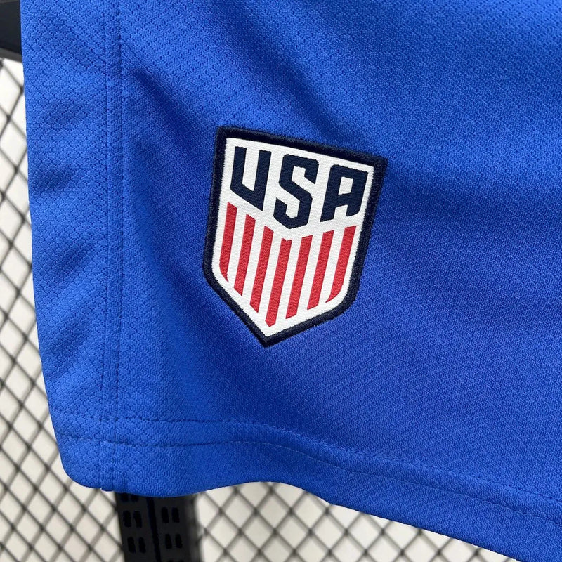 Kit Infantil Estados Unidos Home (1) 2025/26 Nike, uniforme oficial branco com detalhes em azul e vermelho, composto por camisa e shorts, disponível dos 3-4 aos 12-13 anos."