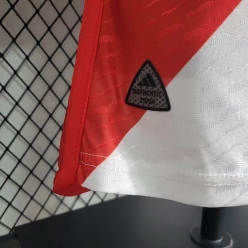 Texto alternativo para imagem:
"Camisa River Plate Home (1) 2023/24 Adidas Jogador Masculina branca com faixa diagonal vermelha, escudo aplicado em silicone 3D, logo Adidas e tecnologia HEAT.RDY, versão oficial usada pelos jogadores."

