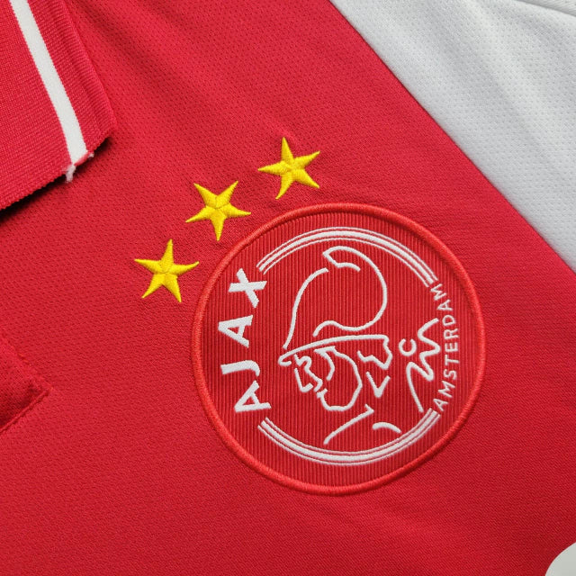 "Camisa Ajax Home (1) 2024/25 Adidas Torcedor Masculina oficial, branca com faixa vermelha central, escudo bordado e logo Adidas, versão torcedor da temporada 24/25."