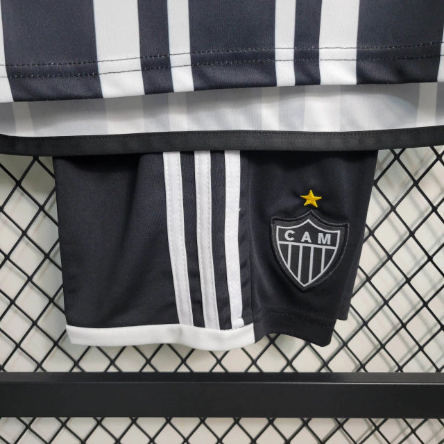 Kit Infantil Atlético Mineiro Home (1) 2023/24 Adidas – camisa listrada preta e branca com escudo bordado, shorts preto e meiões inclusos, uniforme oficial para pequenos torcedores do Galo."
