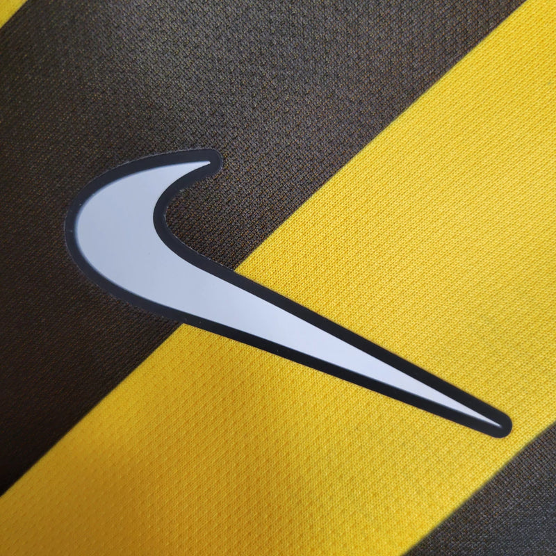 Camisa Al-Ittihad Home I 2023/24 Nike Torcedor Masculina amarela com detalhes em preto, uniforme titular do Al-Ittihad Club da Arábia Saudita, modelo torcedor com tecido leve e tecnologia Dri-FIT para absorção de suor."