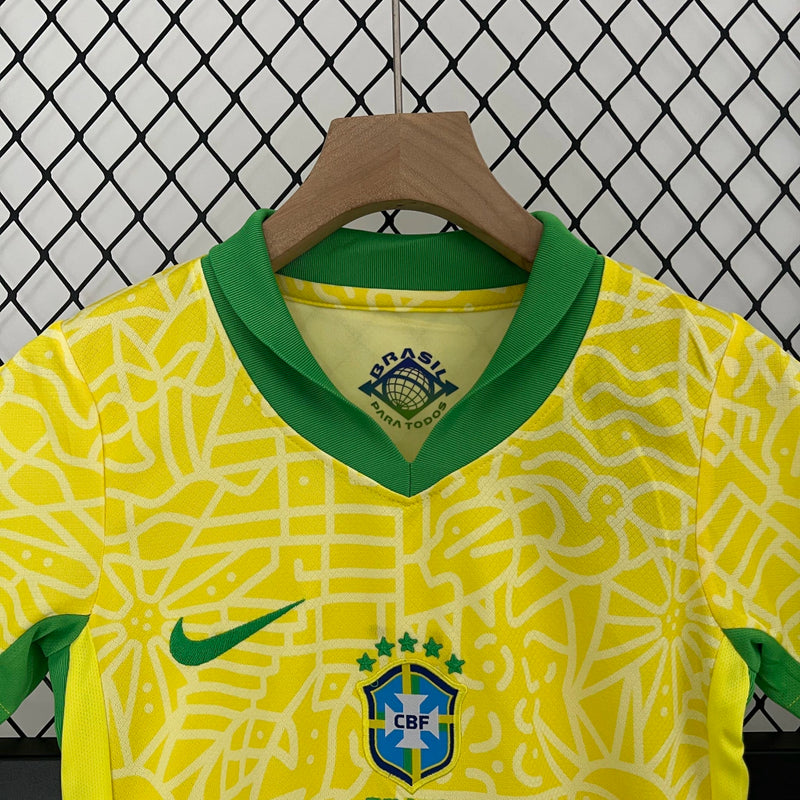 Kit Infantil Brasil Home 2024/25 Nike, camisa amarela com detalhes em verde e azul, shorts e meias combinando, uniforme oficial da Seleção Brasileira para torcedores mirins.