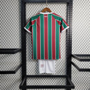 "Kit Infantil Fluminense Home 2023/24 Umbro completo para crianças, com camisa listrada verde, branco e grená, escudo bordado do Fluminense, short oficial combinando, ideal para pequenos torcedores mostrarem orgulho tricolor em treinos e jogos."