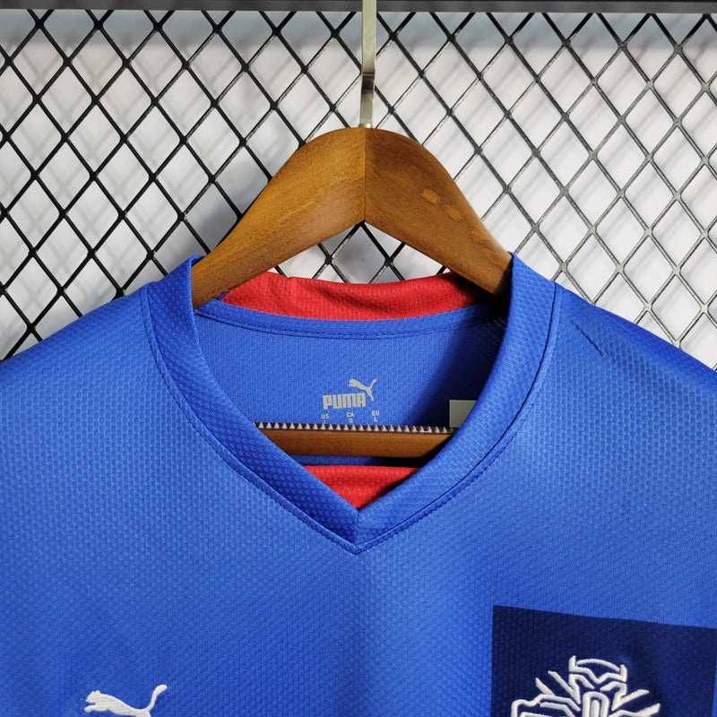 "Camisa Islândia Home I 2022/23 Puma masculina azul com detalhes em branco e vermelho, gola careca, mangas curtas e tecido leve respirável para torcedores"