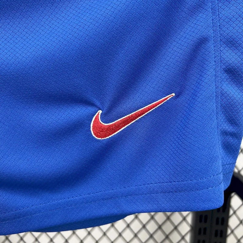 Kit Infantil Estados Unidos Home (1) 2025/26 Nike, uniforme oficial branco com detalhes em azul e vermelho, composto por camisa e shorts, disponível dos 3-4 aos 12-13 anos."