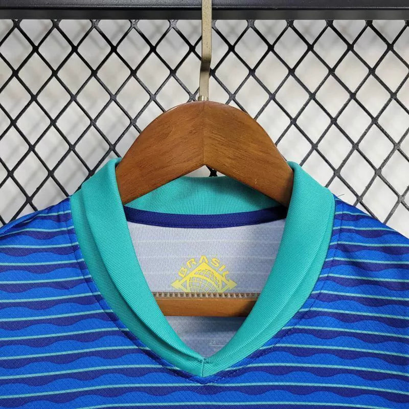 "Kit Infantil Brasil Away 2024/25 Nike, camisa azul com detalhes em verde e amarelo, shorts e meias combinando, uniforme oficial da Seleção Brasileira para torcedores mirins."