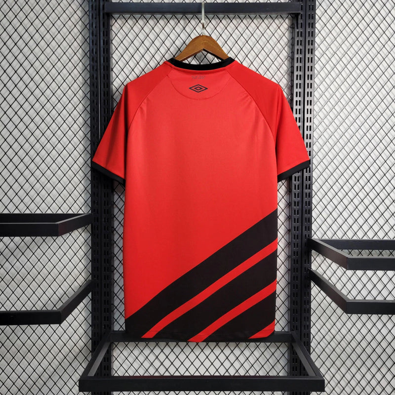 Camisa Athletico Paranaense Home (1) 2023/24 Umbro Torcedor Masculina com escudo oficial bordado e logo Umbro estampado, modelo clássico vermelho e preto do clube paranaense.