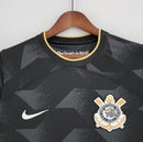 Camisa Corinthians Away II 2022/23 Nike Torcedor Masculina na cor preta com detalhes dourados, escudo bordado no peito esquerdo e logo Nike no lado direito, pendurada em cabide sobre fundo branco.