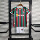 "Kit Infantil Fluminense Home 2023/24 Umbro completo para crianças, com camisa listrada verde, branco e grená, escudo bordado do Fluminense, short oficial combinando, ideal para pequenos torcedores mostrarem orgulho tricolor em treinos e jogos."