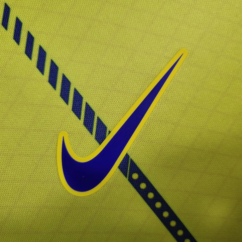 Camisa Al-Nassr Home (1) 2023/24 Nike Torcedor Masculina amarela com detalhes azuis, escudo do Al-Nassr e logo Nike bordados, modelo oficial usado por Cristiano Ronaldo."
