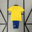 Kit Infantil Brasil Home 1994 Umbro, camisa amarela com detalhes verdes e azuis, shorts e meias combinando, uniforme retrô oficial para crianças de 3 a 13 anos torcedoras da Seleção Brasileira."