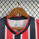 Kit Infantil São Paulo FC Away 2024/25 New Balance com camisa branca, detalhes em vermelho e preto, escudo bordado do SPFC, shorts combinando, uniforme oficial para crianças de 3 a 13 anos, torcedor infantil, conforto e mobilidade, peça licenciada"